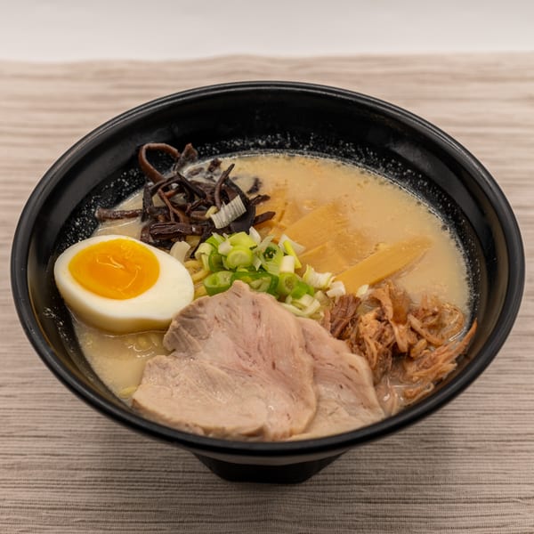 A close-up of Tanpopo Ramen's ramen bowl, featuring pork, egg, bamboo shoots, and green onions.
