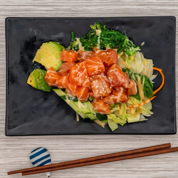 Tanpopo Ramen's salmon poke salad with avocado, seaweed, and lettuce on a black plate.
